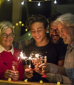 group of two seniors and an adult and a teenager together having fun with sparlers the new year to celebrate - happy family with lights