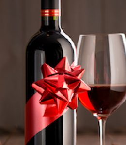 Wine bottle gift with red wine glass, autumn leaves and wooden surface on background.